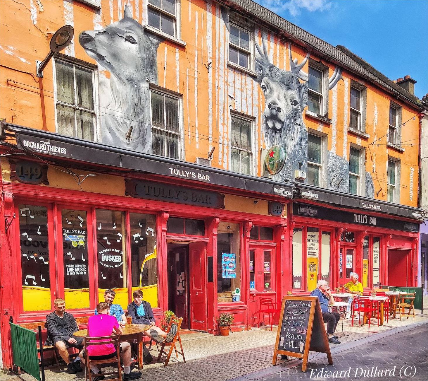 People sitting out at tables in front of Tully's on a sunny day